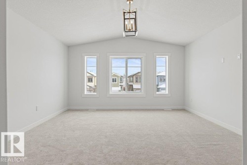 Spacious room featuring vaulted ceilings, light-colored carpeting, and three windows providing views of the neighborhood - 5018 53 Avenue, Calmar, AB - Indoor Photo Showing Other Room
