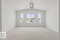Spacious room featuring vaulted ceilings, light-colored carpeting, and three windows providing views of the neighborhood - 