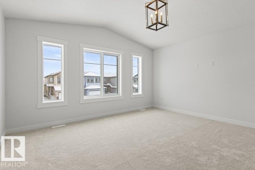 This room features light-colored carpet flooring, white walls, and a vaulted ceiling with a decorative light fixture - 5018 53 Avenue, Calmar, AB - Indoor Photo Showing Other Room
