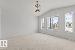 Spacious room with vaulted ceilings, featuring light-colored carpeting, and a series of windows that provide natural illumination - 