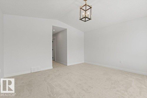 This room features light-colored carpeting, white walls, and a modern ceiling light fixture - 5018 53 Avenue, Calmar, AB - Indoor Photo Showing Other Room