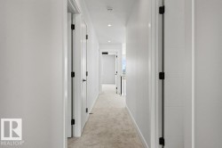 This hallway features light-colored walls and carpeted flooring - 