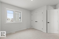 This room features light-colored carpeting, a window with white trim, and two white doors with black hardware - 