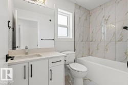 The bathroom features a vanity with a rectangular sink, a mirror, and a toilet - 