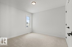 This room features a window providing natural light, light-colored carpeting, and a ceiling-mounted light fixture - 