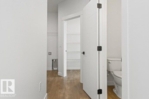 This property features light-colored walls and wood-look flooring throughout - 5018 53 Avenue, Calmar, AB - Indoor Photo Showing Other Room