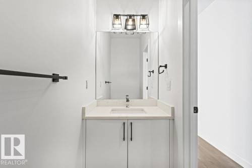 Bathroom vanity with a light-colored countertop, a rectangular sink, and a modern light fixture - 5018 53 Avenue, Calmar, AB - Indoor Photo Showing Bathroom