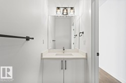 Bathroom vanity with a light-colored countertop, a rectangular sink, and a modern light fixture - 