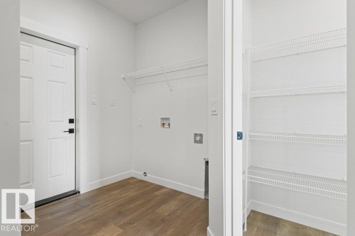 Utility area with wood-look flooring, a white paneled door, and built-in wire shelving - 5018 53 Avenue, Calmar, AB - Indoor