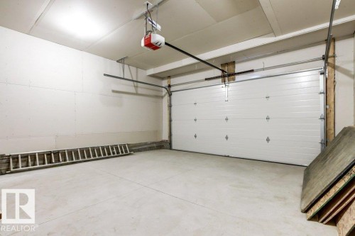 This property features a spacious garage with a light-colored concrete floor, a white sectional garage door, and an automatic garage door opener - 5018 53 Avenue, Calmar, AB - Indoor Photo Showing Garage