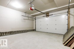 This property features a spacious garage with a light-colored concrete floor, a white sectional garage door, and an automatic garage door opener - 