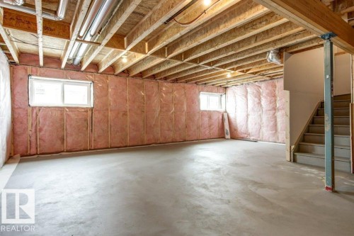 Spacious unfinished lower level featuring a concrete floor, exposed wood beams, and two windows providing natural light - 5018 53 Avenue, Calmar, AB - Indoor Photo Showing Basement