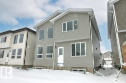 The property features light gray siding, white trim, and a prominent white rear entry door - 