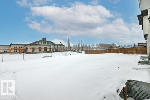 The property features an expansive, snow-covered yard with a wooden fence - 5018 53 Avenue, Calmar, AB - Outdoor