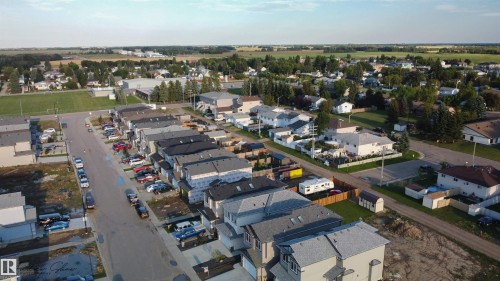 This aerial view showcases the property within a community featuring residential homes, paved streets, and a green field area - 5018 53 Avenue, Calmar, AB - Outdoor With View