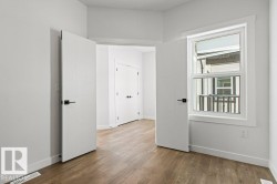 This room features light wood-style flooring, white walls, and a white window frame - 