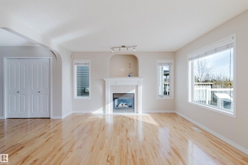 The living room features hardwood floors, a fireplace with a white mantel and tiled surround, and windows providing natural light - 1135 112 Street, Edmonton, AB - Indoor Photo Showing Living Room With Fireplace