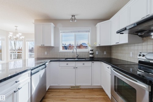 The kitchen features white cabinetry, dark countertops, and stainless steel appliances - 1135 112 Street, Edmonton, AB - Indoor Photo Showing Kitchen With Double Sink