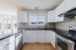 The kitchen features white cabinetry, dark countertops, and stainless steel appliances - 