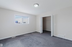 This room features light-colored walls and dark carpeting, with a window providing natural light - 