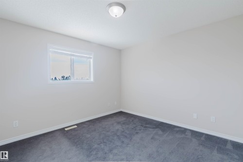 This room features light-colored walls, a window providing natural light, and dark carpet flooring - 1135 112 Street, Edmonton, AB - Indoor Photo Showing Other Room