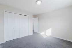 This room features neutral-toned walls, gray carpeting, and white bi-fold closet doors - 