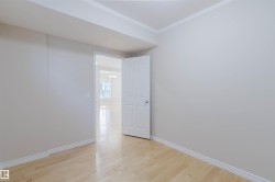 This room features light-colored hardwood flooring, white baseboards, and a white interior door - 