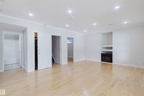Spacious room featuring light-toned wood flooring, recessed lighting, and a built-in fireplace with shelving - 1135 112 Street, Edmonton, AB - Indoor With Fireplace