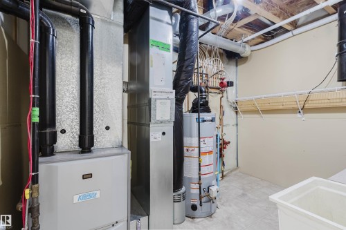 The property features a utility area with mechanical systems, including a water heater and furnace, along with a utility sink and wall-mounted shelving - 1135 112 Street, Edmonton, AB - Indoor