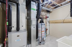 The property features a utility area with mechanical systems, including a water heater and furnace, along with a utility sink and wall-mounted shelving - 