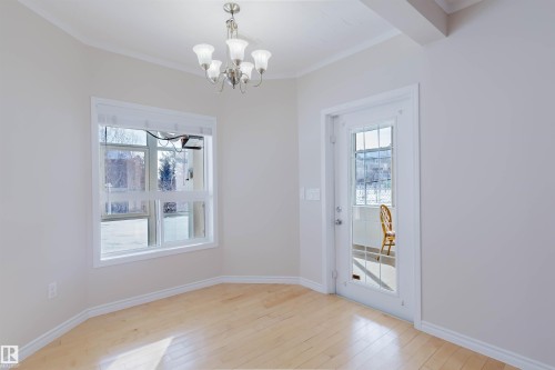 This bright room features light-toned hardwood flooring, a large window, and a glass-paneled door - 1135 112 Street, Edmonton, AB - Indoor Photo Showing Other Room