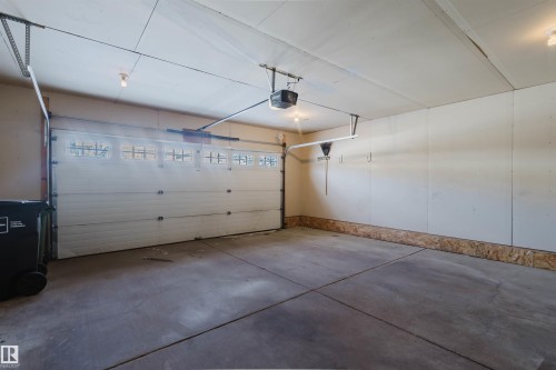 The property features a garage with a concrete floor, an overhead door with window panels, and exposed ceiling joists - 1135 112 Street, Edmonton, AB - Indoor Photo Showing Garage