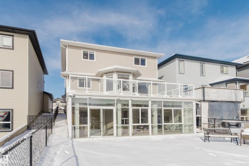 The property features a multi-story exterior with light-colored siding, a glass-enclosed sunroom, and a glass-paneled deck - 1135 112 Street, Edmonton, AB - Outdoor