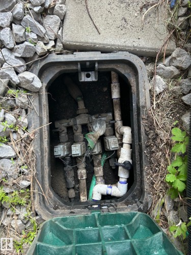 Utility box containing various pipes and connections, surrounded by gravel and a concrete slab - 1135 112 Street, Edmonton, AB - 