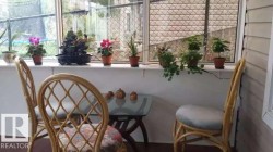 The property features a sunroom with large windows, a glass-top table, and rattan chairs - 
