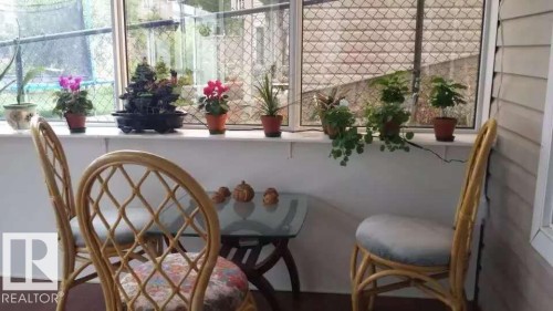 The property features a sunroom with large windows, a glass-top table, and rattan chairs - 1135 112 Street, Edmonton, AB - Indoor Photo Showing Other Room