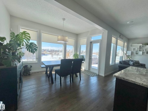 The property features a bright dining area with an abundance of windows offering extensive views, hardwood floors, and a modern chandelier - 5333 21A Avenue, Edmonton, AB - Indoor