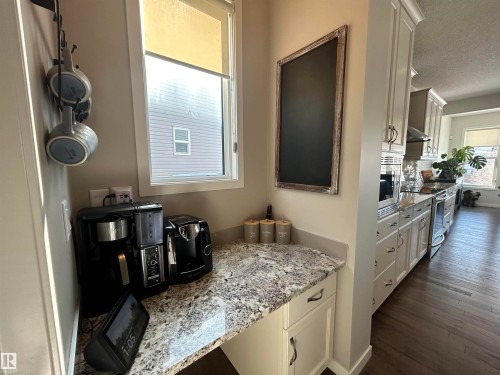 This kitchen features extensive white cabinetry with dark hardware and a light-colored speckled countertop - 5333 21A Avenue, Edmonton, AB - Indoor