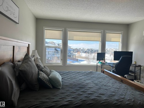 This room features a large window with roller shades, providing expansive views of the surrounding neighborhood and distant snow-covered hills - 5333 21A Avenue, Edmonton, AB - Indoor Photo Showing Bedroom