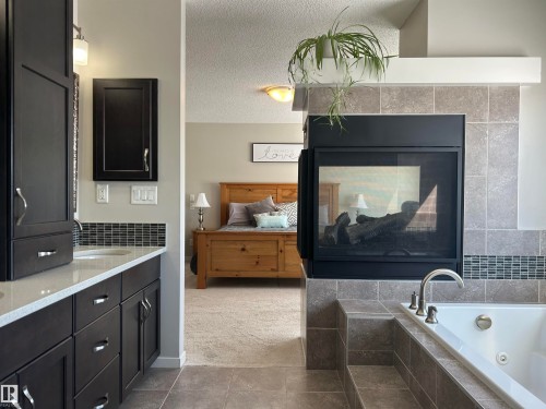 The property features a bathroom with dark wood cabinetry, a light-colored countertop, and a tiled backsplash - 5333 21A Avenue, Edmonton, AB - Indoor Photo Showing Bathroom