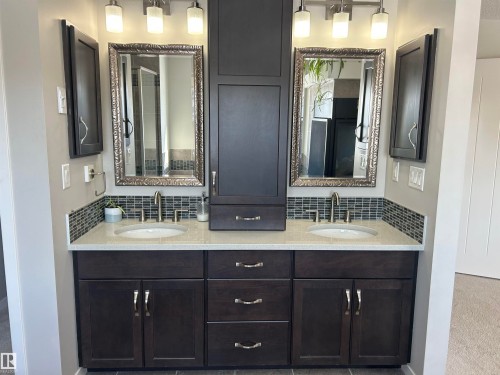 This bathroom features a dual vanity with dark wood cabinetry, white countertops, and contemporary silver-toned hardware - 5333 21A Avenue, Edmonton, AB - Indoor Photo Showing Bathroom