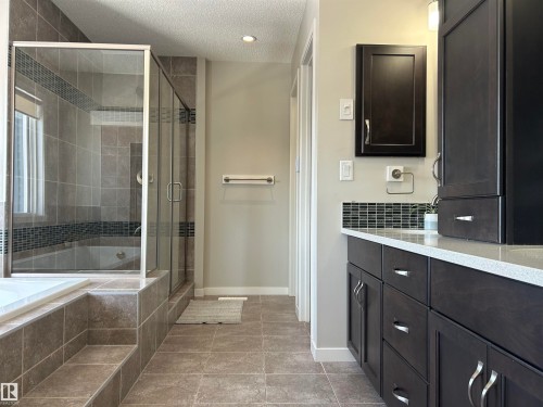 The bathroom features a glass-enclosed shower, a built-in bathtub, and dark wood cabinetry with a light-colored countertop - 5333 21A Avenue, Edmonton, AB - Indoor Photo Showing Bathroom