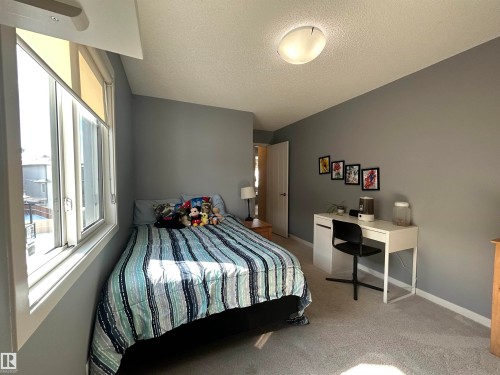 Bedroom featuring light gray walls, a window with roller shades, and gray carpet flooring - 5333 21A Avenue, Edmonton, AB - Indoor Photo Showing Bedroom