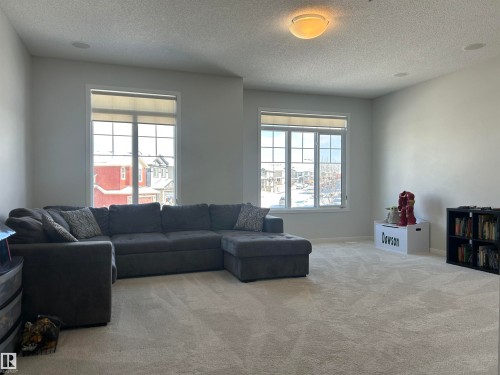 This spacious living area features light-colored carpeting, large windows, and a ceiling light fixture - 5333 21A Avenue, Edmonton, AB - Indoor Photo Showing Living Room