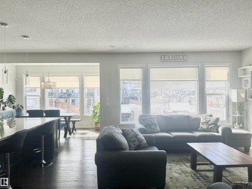 The spacious living area features large windows providing ample natural light, a dark wood floor, and a rug with a geometric pattern - 5333 21A Avenue, Edmonton, AB - Indoor Photo Showing Living Room