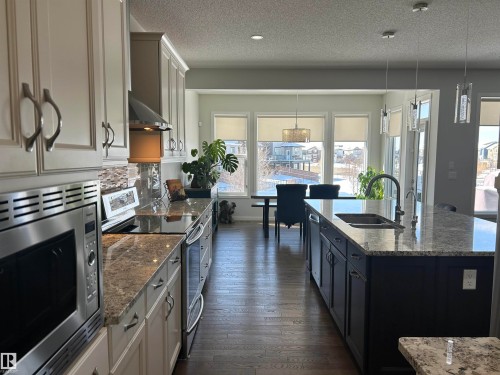 The gourmet kitchen features stainless steel appliances, granite countertops, and an expansive island with a sink - 5333 21A Avenue, Edmonton, AB - Indoor Photo Showing Kitchen With Double Sink With Upgraded Kitchen