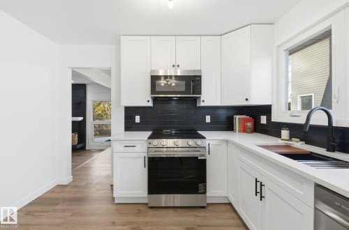 Kitchen featuring stainless steel appliances, healthy amount of natural light, and white cabinetry - 2722 104A Street, Edmonton, AB - Indoor Photo Showing Kitchen