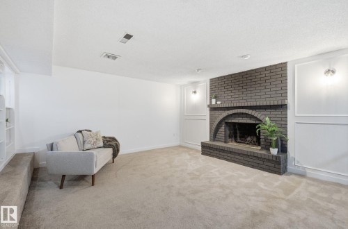 Spare room featuring carpet, textured ceiling, recessed lighting, two levels and a black brick fire place. - 2722 104A Street, Edmonton, AB - Indoor Photo Showing Living Room With Fireplace