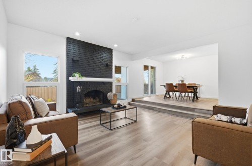 Living room featuring a brick fireplace and light wood-style flooring - 2722 104A Street, Edmonton, AB - Indoor Photo Showing Living Room With Fireplace