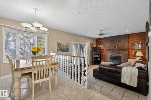 The property features tiled flooring throughout, a dining area with a bay window, and a living area with a brick fireplace and wood paneling - 5604 174 Street, Edmonton, AB - Indoor Photo Showing Other Room With Fireplace
